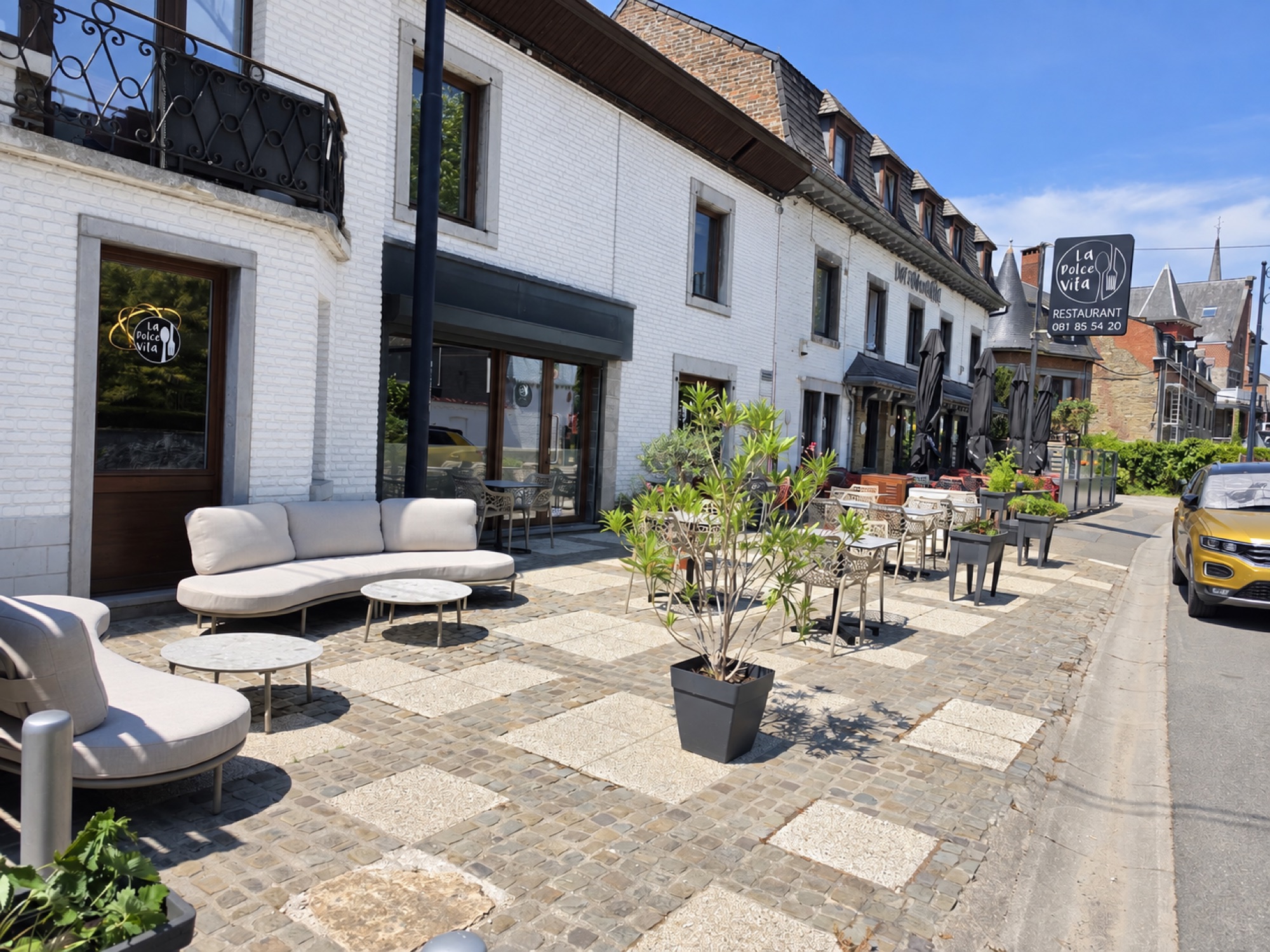 La terrasse en damier de pierre de La Dolce Vita, canapés clairs et façade blanche